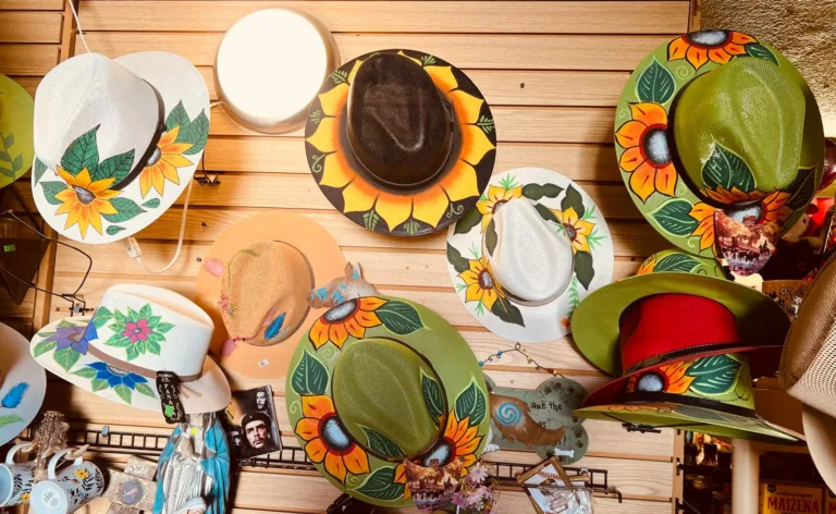 Hand painted decorative hats with sunflower designs displayed inside Alma Artesanal in Hatch, New Mexico